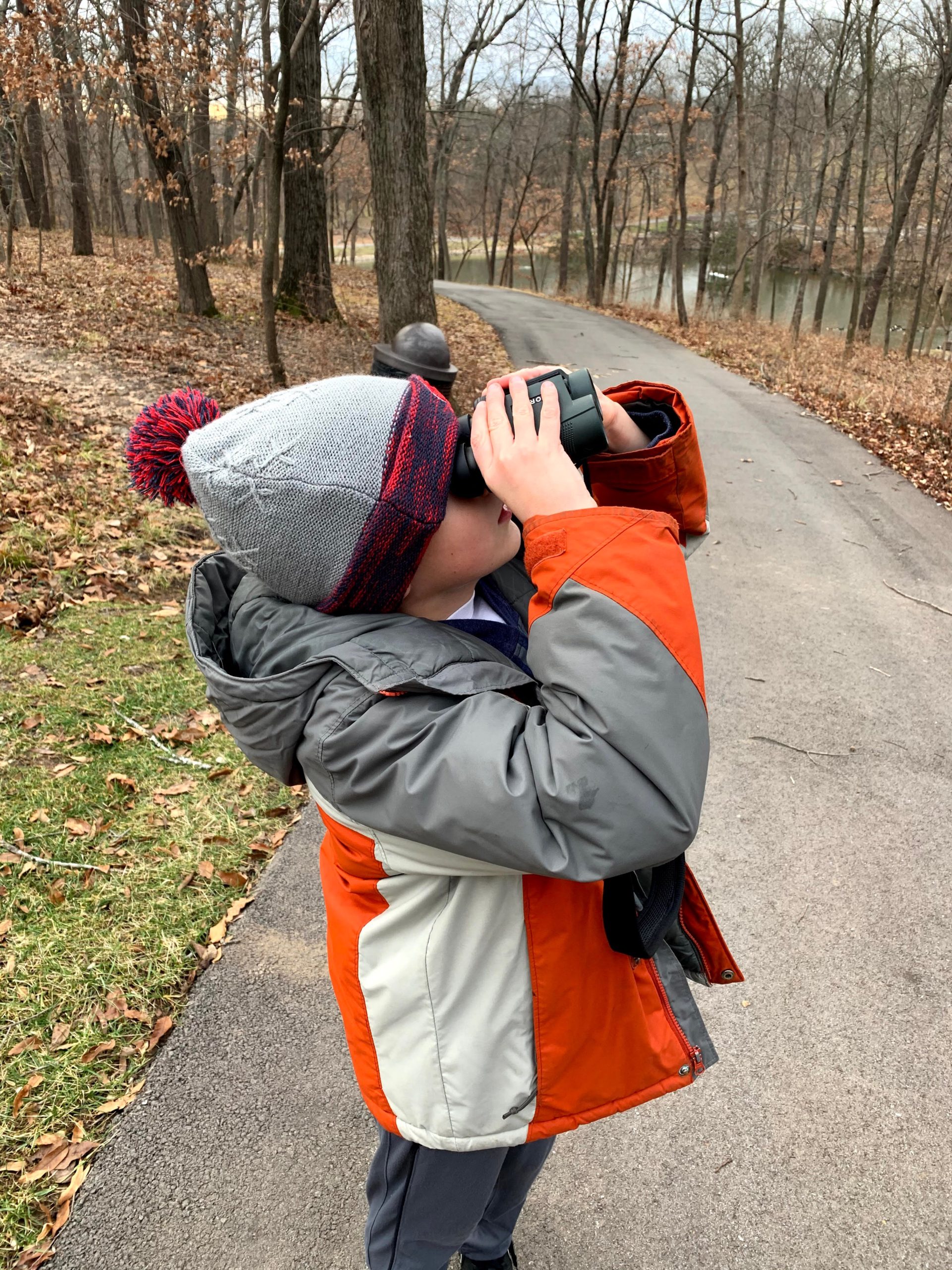 A boy on path birdwatching with binoculars